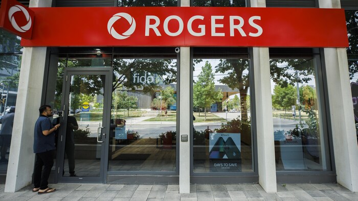 Un homme attend à la porte d'un magasin de téléphones cellulaires de Rogers à Toronto.