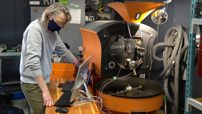 Un homme contrôle l'évolution de la température de sa machine à torrifier le café.