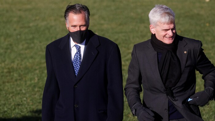 Mitt Romney, portant un masque, et Bill Cassidy, mettant le sien dans sa poche, marchent sur le terrain de la Maison-Blanche.