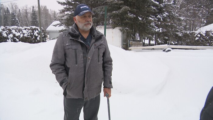 Ron Cormier debout dans la neige, une canne à la main.