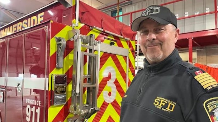 Un chef pompier en uniforme souriant à l'intérieur d'une caserne.