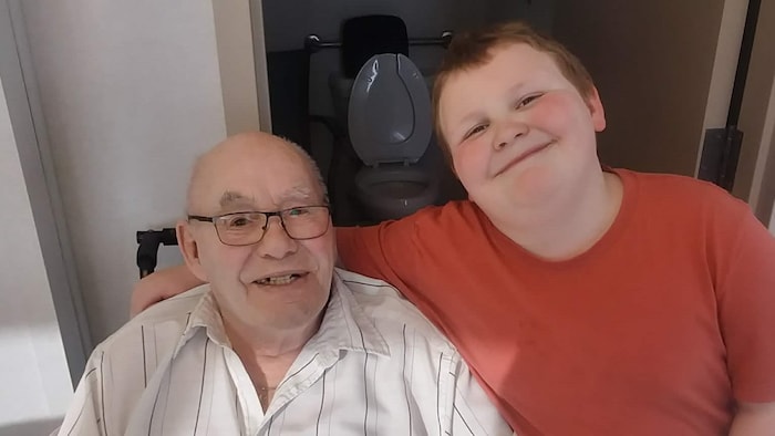 Ronald Shattler et son petit-fils sourient à la caméra.