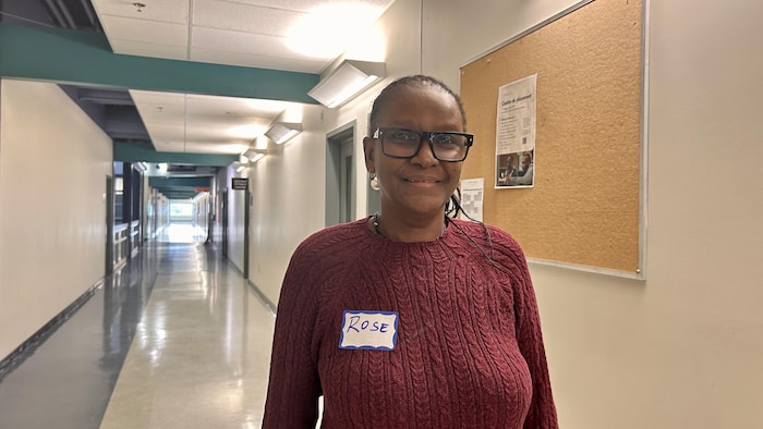 Rose Kana, souriante, pose dans un long corridor.