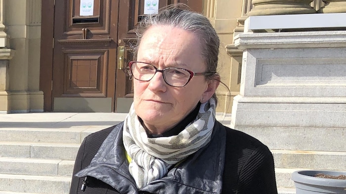 Roseline Pelletier est debout à l'extérieur. Une journaliste lui met un micro sous le menton.