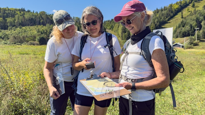 Portrait d'Annie Lavoie, Isabelle Renaud et Nathalie Collin tenant des boussoles et une carte.
