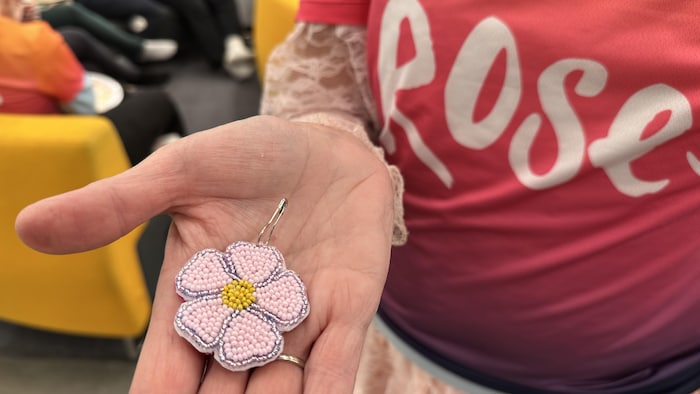 Gros plan d'une rose perlée dans la main d'une femme.