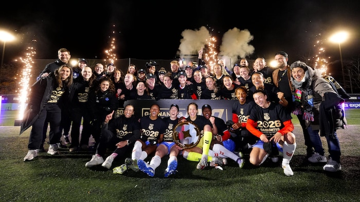 Des joueuses de soccer posent pour la caméra avec le trophée.