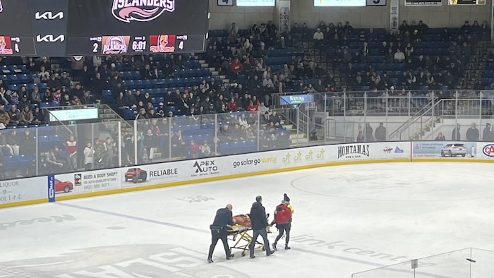 Trois secouristes évacuent le joueur qui repose sur une civière.