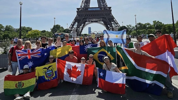 De nombreux étudiants devant la tour Eiffel à Paris, arborant des drapeaux aux couleurs de leurs pays.