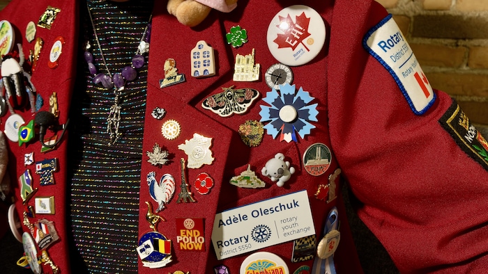 Une veste rouge avec de nombreux épinglettes, comme un pin du mont Saint-Michel, ou encore de Vimy, pour représenter les liens avec la France.