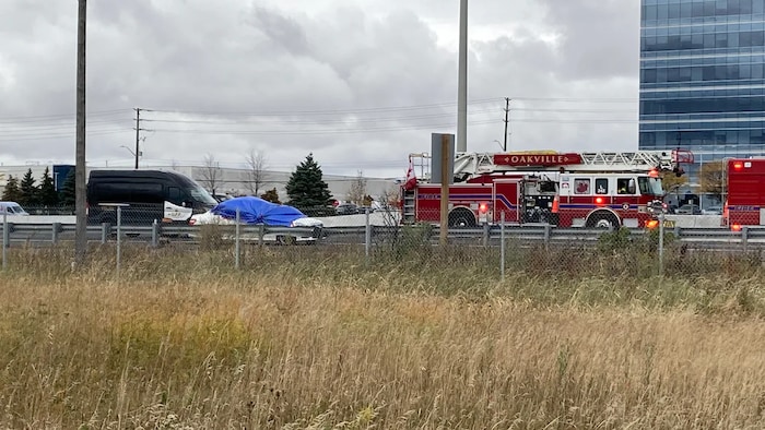 Des camions de pompiers et un véhicule accidenté sur le bord de l'autoroute.
