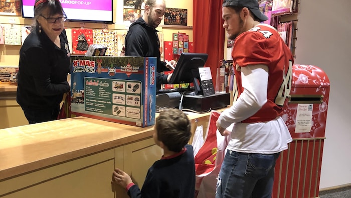 Un joueur du Rouge et Or accompagne un des enfants à la caisse.