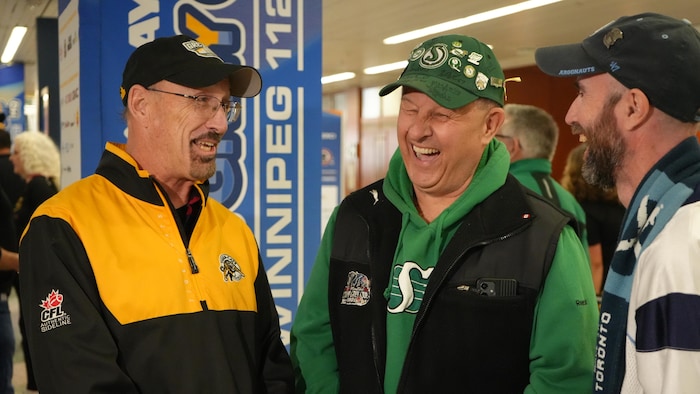 Trois hommes arborant les couleurs des Tiger-Cats d'Hamilton, des Roughriders de la Saskatchewan et des Argonauts de Toronto.