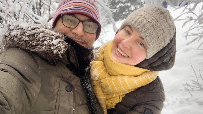 Un homme et une femme souriant sous la neige.