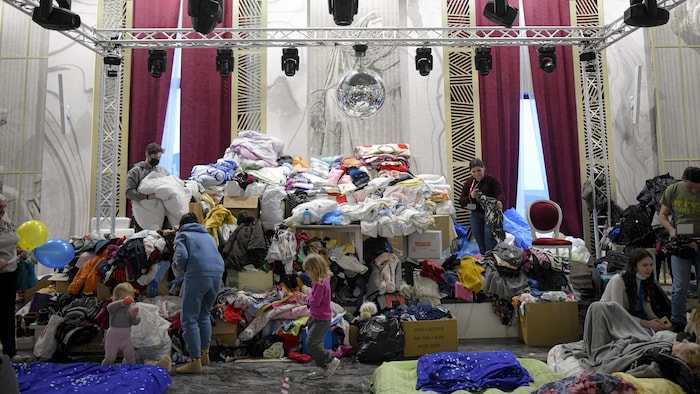 Volunteers sift through piles of clothing donations into a ballroom that has been turned into a temporary shelter for refugees.