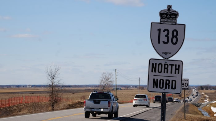 Le panneau de la route 138 en premier plan avec des voitures en arrière plan.