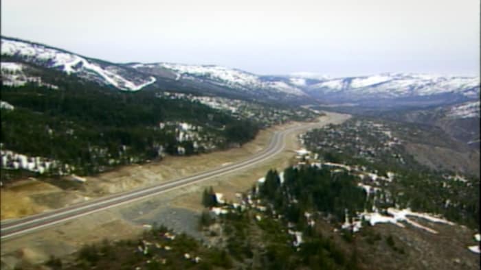 Une vallée entourée de montagnes, avec la route Coquihalla en son centre.
