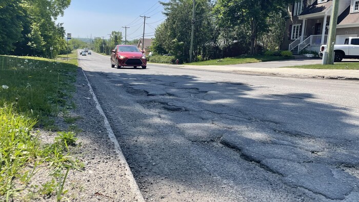 Une voiture roule sur une route endommagée.