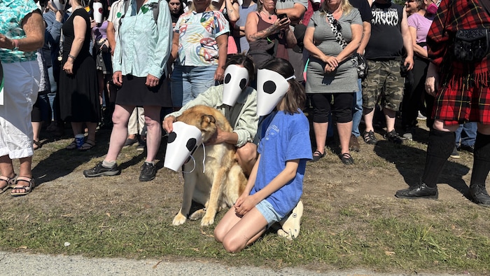 Deux personnes et un chien qui portent des masques. 