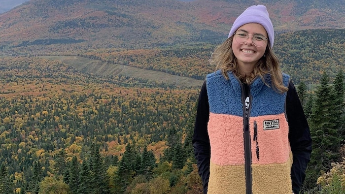 Une jeune enseignante posant devant un paysage montagneux et automnal