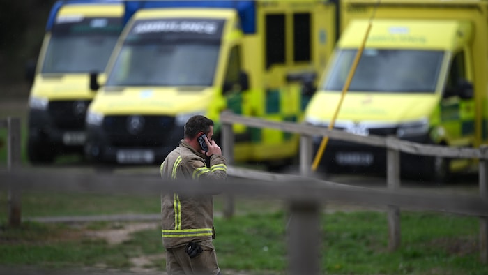 Un membre des services d'urgence passe devant des véhicules garés au Fairford Youth Football Club, le 27 septembre 2026, à Fairford, en Angleterre. 