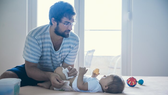Un père change la couche de son enfant.