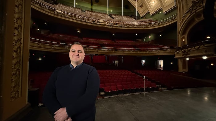 Ruben Ramalheiro pose sur la scène du théâtre avec les sièges vides à l'arrière.