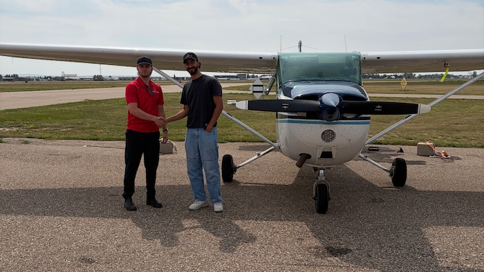 Rudi Slagter et un autre homme se serrent la main devant un petit avion.