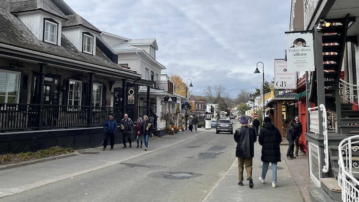 Des gens marchent sur les trottoirs d'une rue de Baie-Saint-Paul.