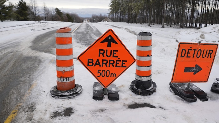 Des panneaux et des cônes orange qui signalent un détour en raison d'une rue barrée.