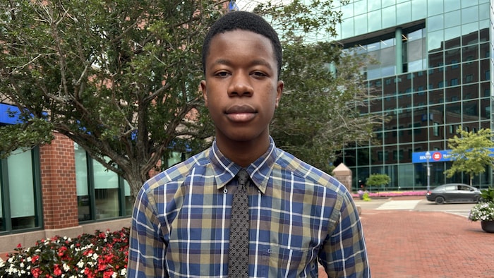 Rayan Kingala est debout sur le trottoir en brique rouge sur la rue Mechanic à Moncton. 