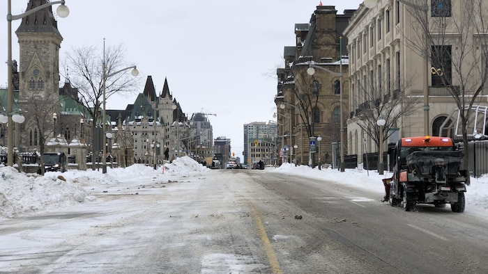 Un petit camion de la Ville déneige le côté de la chaussée.