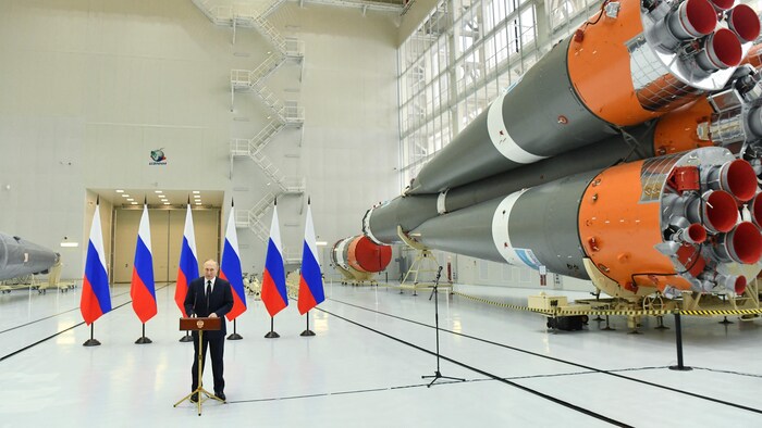 Russian President Vladimir Putin speaks next to cutting missiles.