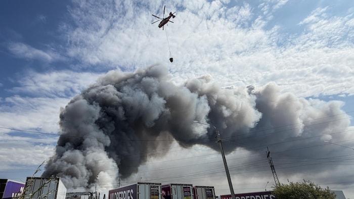 Un hélicoptère de lutte contre les incendies s'apprête à larguer un chargement d'eau lors d'un incendie survenu dans le complexe logistique de la société russe de commerce électronique Wildberries, près de la ville de Podolsk, dans la banlieue de Moscou, le 16 août 2026.