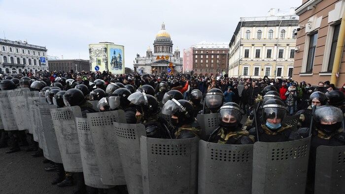 Des dizaines de policiers sont regroupés avec leurs boucliers devant des manifestants.