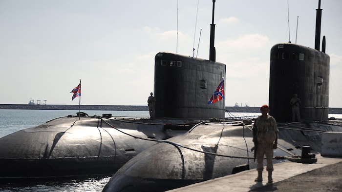 Un soldat se tient devant un sous-marin.