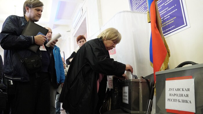 Une femme dépose son bulletin de vote dans une boîte. 