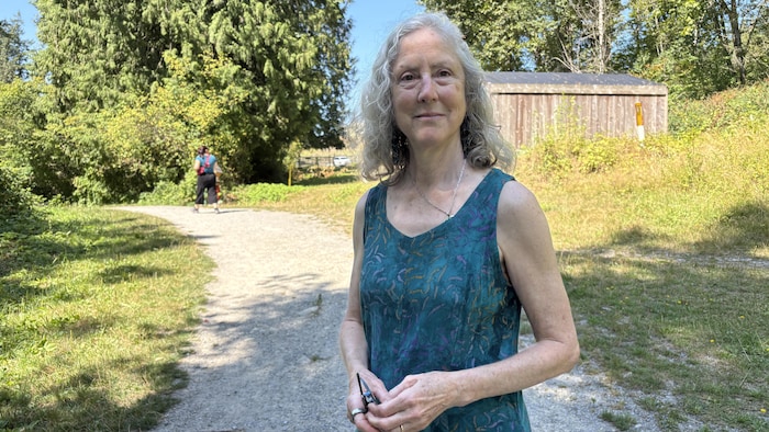 Une femme debout devant un sentier.