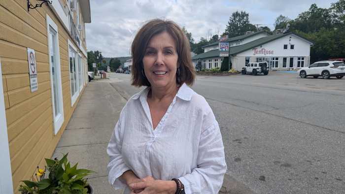 Sylvie Lévesque sourit à la caméra en posant à l'extérieur, avec le restaurant TemRose derrière elle.