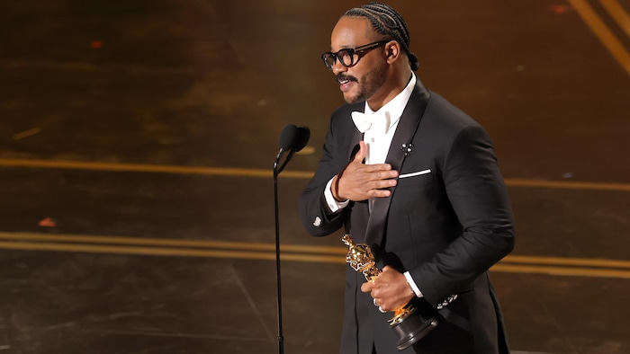 Le cinéaste fait ses remerciements sur scène avec son Oscar, une main sur le cœur. 