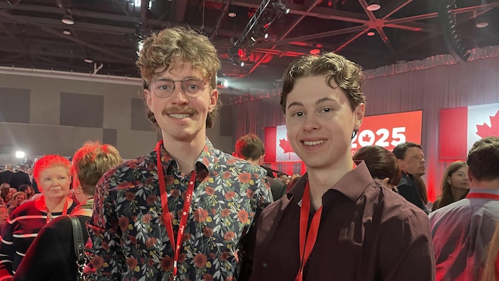 Deux jeunes hommes debout sourient pour la photo durant un rassemblement du Parti libéral du Canada.