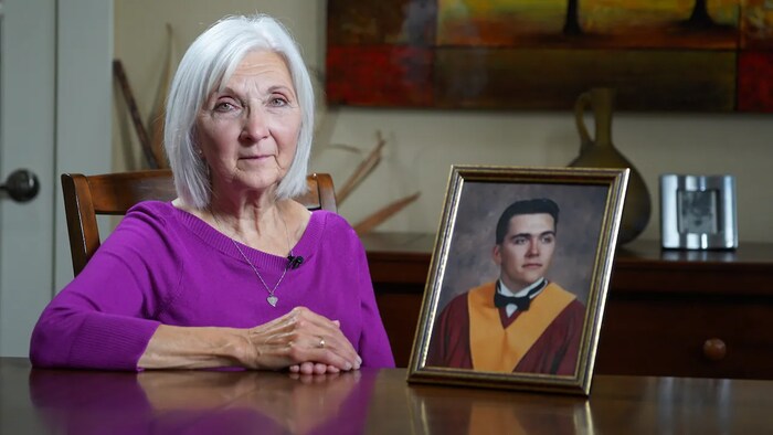 Brenda Eamer assise à côté du portrait de son fils Ryan Eamer.