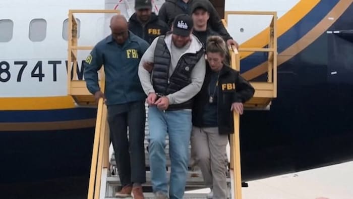 Ryan Wedding débarquant d’un avion à son arrivée aux États-Unis, entouré d’agents du FBI.