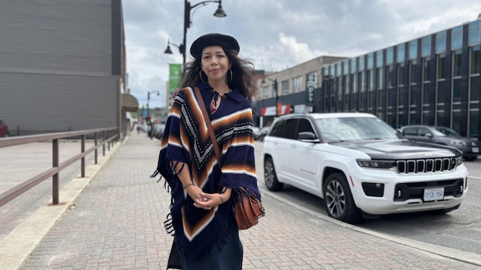 Portrait de Rylee Peltier portant un pancho dans une rue du Grand Sudbury.