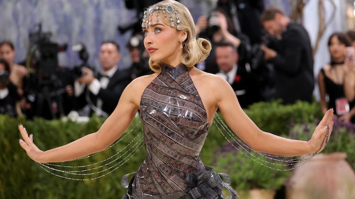 A woman looks up, wearing a dress that looks like it was made from film stock.