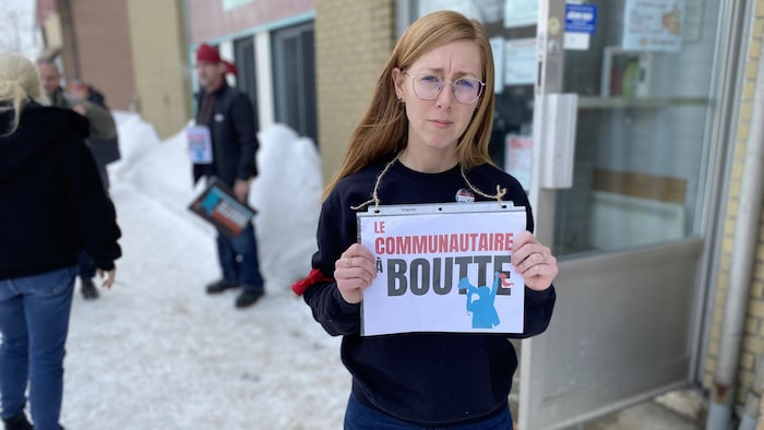 Sabrina Robitaille tient une pancarte en main à l'extérieur en hiver. 
