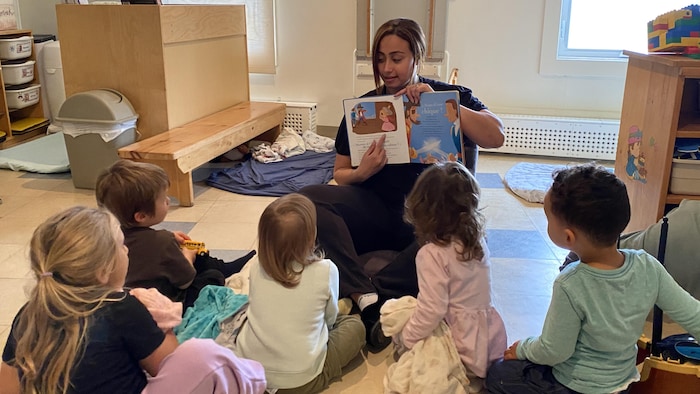 Une éducatrice lit un livre à des enfants.