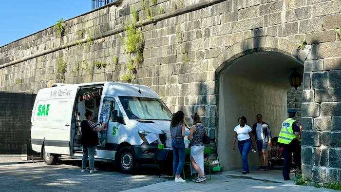 Une fourgonnette stationnée près d'un mur de pierres.