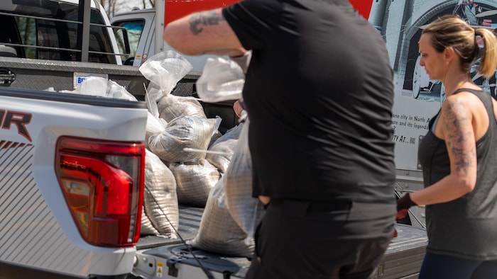 Une personne dépose des sacs de sable dans la boîte d'une camionnette.