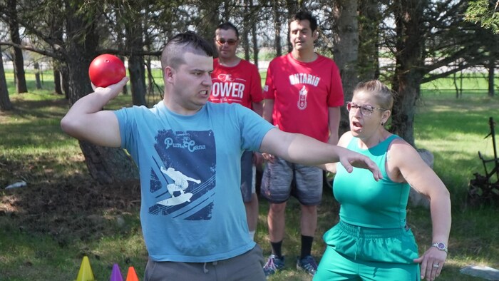 Une mère regarde son fils lancer un poids. 